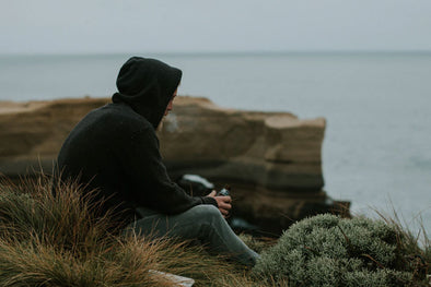A man overlooking a body of water, exhaling smoke