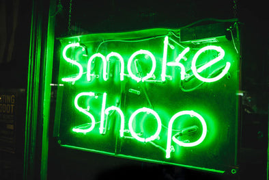A neon green 'Smoke Shop' sign
