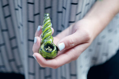 Close-up of a packed glass pipe in a woman’s hand